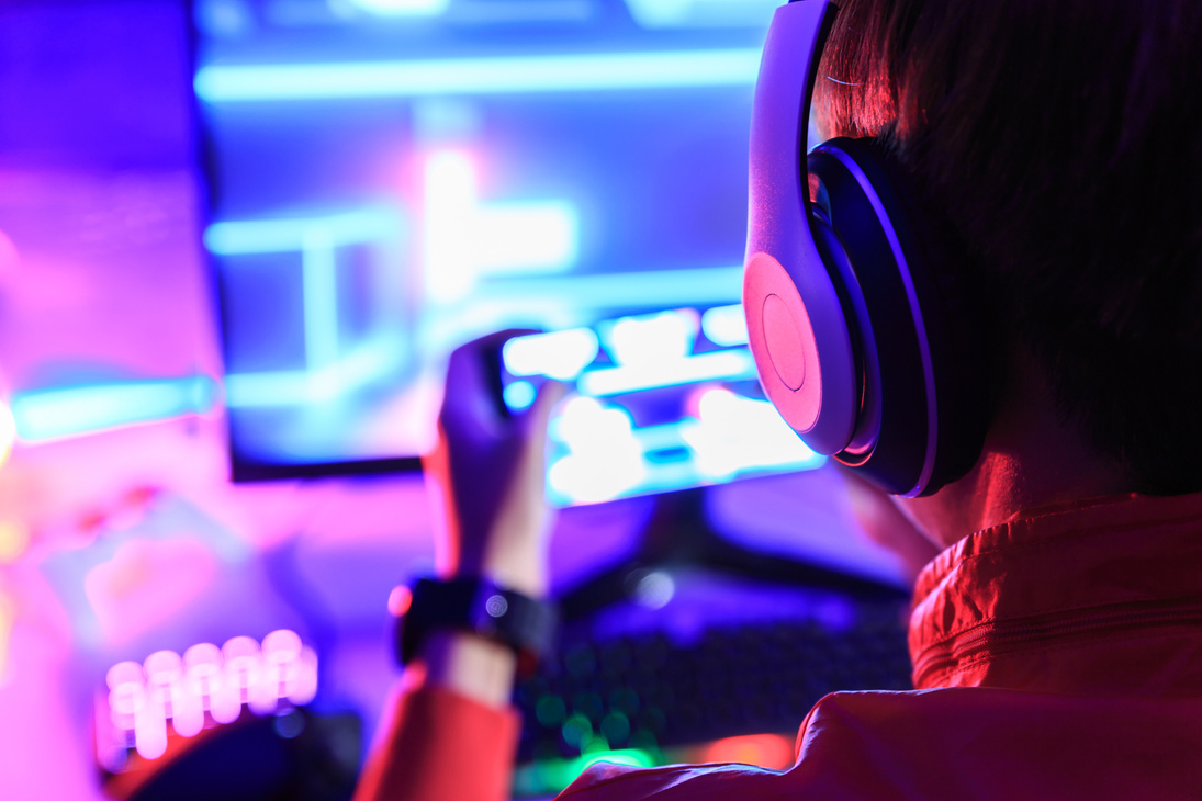 Gamer playing online game on PC in dark room.
